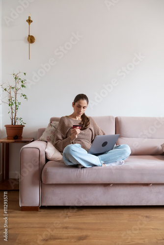 Young woman shopping online using laptop and credit card at home