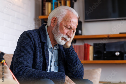 Sad senior man sitting with head in hands photo