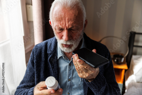 Senior man with pill bottle talking on cellphone photo