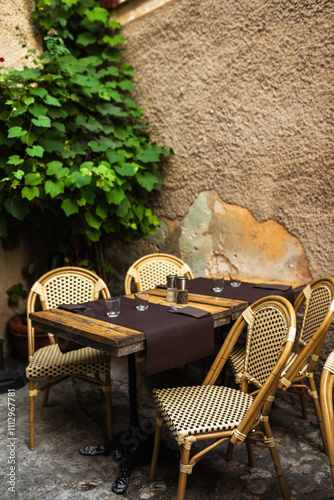 Tables with wooden chairs placed outside a restaurant on the street photo