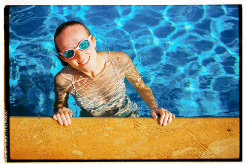 Overhead portrait film photo of a happy woman swimming in the pool photo