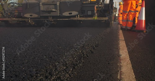 Road workers lay fresh asphalt tarmacadam road surface