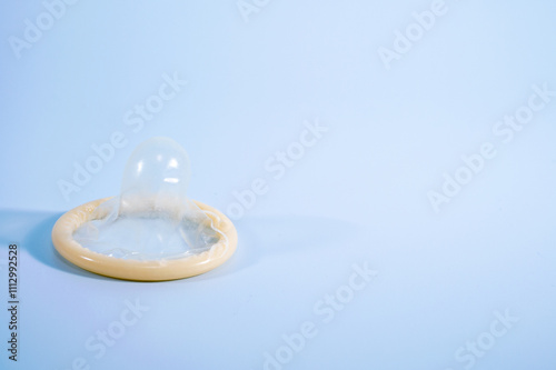 Image of a rolled-up condom on a blue background. Using a condom significantly decreases the risk of gonorrhea, chlamydia, trichomoniasis, hepatitis B, and HIV. photo