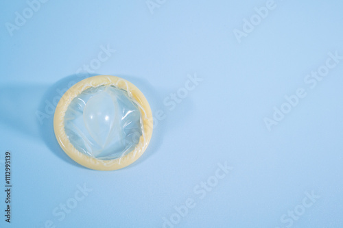 Image of a rolled-up condom on a blue background. Using a condom significantly decreases the risk of gonorrhea, chlamydia, trichomoniasis, hepatitis B, and HIV. photo