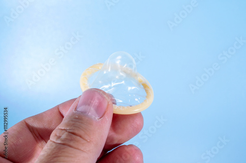 Image of a rolled-up condom on a blue background. Using a condom significantly decreases the risk of gonorrhea, chlamydia, trichomoniasis, hepatitis B, and HIV. photo