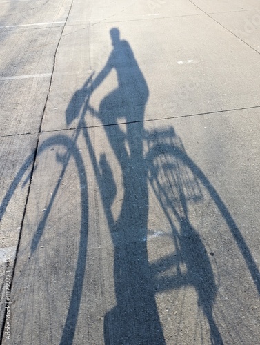 The shadow of a person on a bike with a basket. The person is ready to bike around town to do errands and its helping the environment by choosing to ride instead of drive.