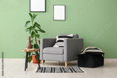 Armchair, houseplant, pouf and coffee table near green wall in room