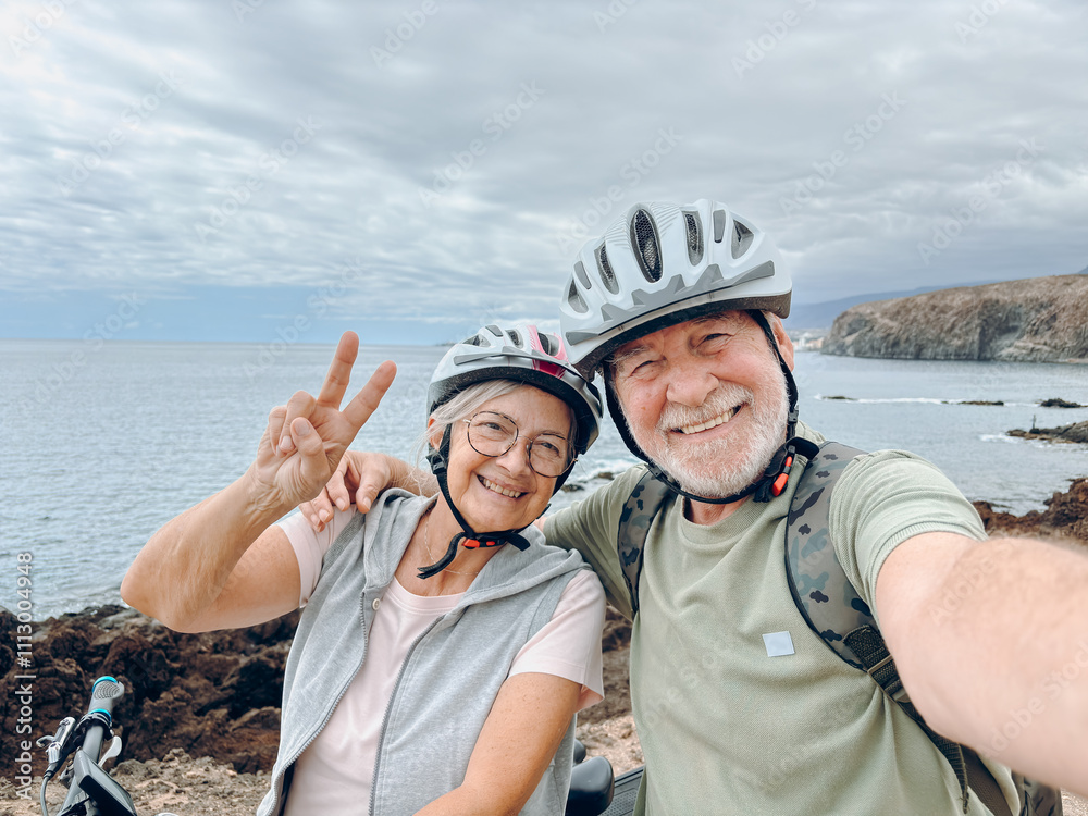 Two happy old mature people enjoying and riding bikes together to be fit and healthy outdoors. Active seniors having fun taking a selfie picture with camera Two happy old mature people enjoying and riding bikes together to be fit and healthy outdoors. Active seniors having fun taking a selfie picture with camera