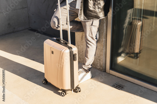Casual Man with Suitcase Leaning Against Building