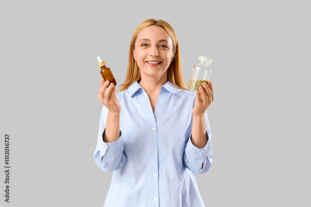 Mature woman with remedy and herbs on light background. Homeopathy concept