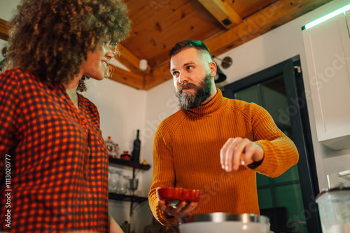 Couple cooking together, adding ingredients in modern kitchen photo