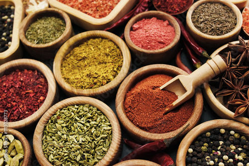 Colorful mix of herb and spice varieties: curry and coriander, turmeric and cumin, paprika and pepper, mustard and salt, cardamon and oregano and saffron. Selective focus, shallow DOF