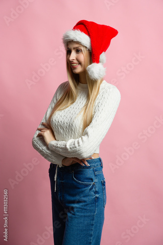 Cheerful woman wearing Santa hat poses against pink background