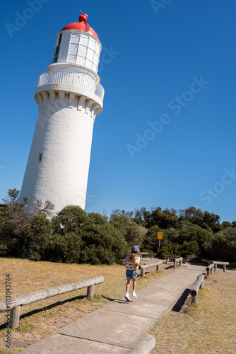 A little girl exploring the lighthouse and skipping to it. photo