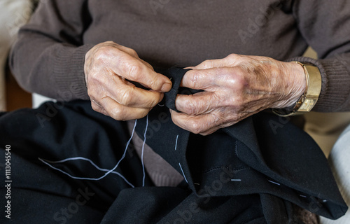 Elderly woman mending her pants at home. photo