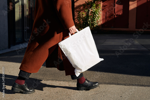 Person walking along a city sidewalk carrying a thermal bag photo