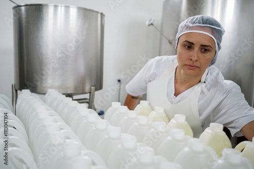 Female worker inspecting production line of milk bottles photo