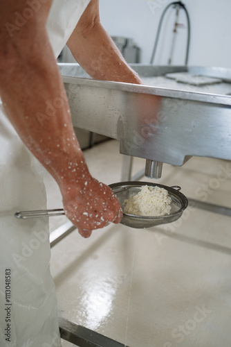 Cheese maker using sieve separating whey from curd photo