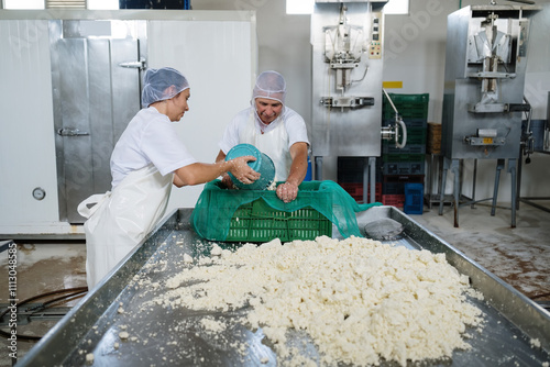 Cheesemakers pour curd into a mold for pressing