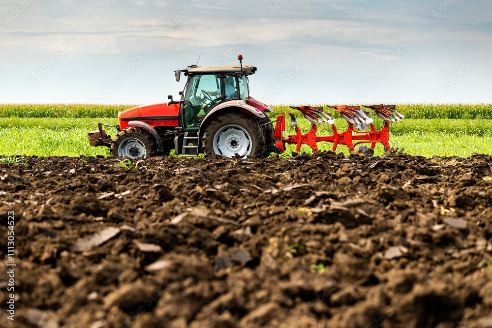 Tractor with plow attachment turns the soil in a vast, green farmland Tractor with plow attachment turns the soil in a vast, green farmland