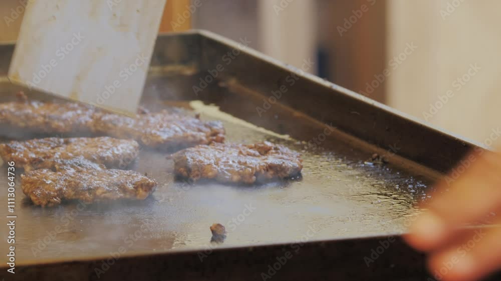 Cooking American fat smash burger with fresh onion on top on grill close-up. Beef or pork cutlet smashing by burger press. The chef in kitchen of the restaurant making Cooking American fat smash burger with fresh onion on top on grill close-up. Beef or pork cutlet smashing by burger press. The chef in kitchen of the restaurant making