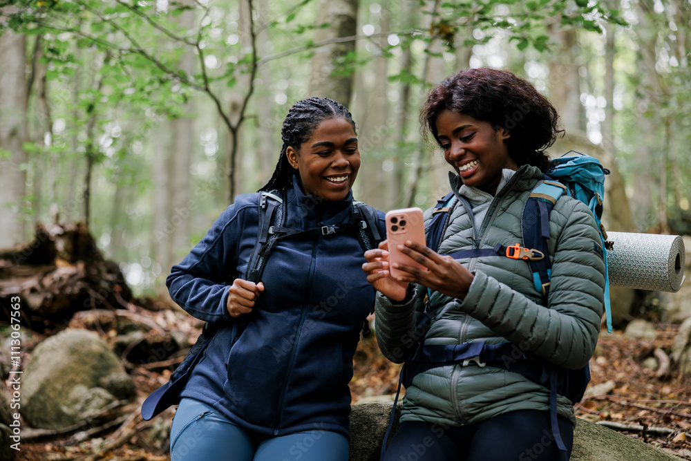 Women hiking and looking at smartphone in a forest Women hiking and looking at smartphone in a forest