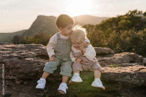 Big brother kissing baby sister at sunset