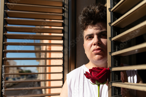Anxious non binary person looking out of a window with shutter