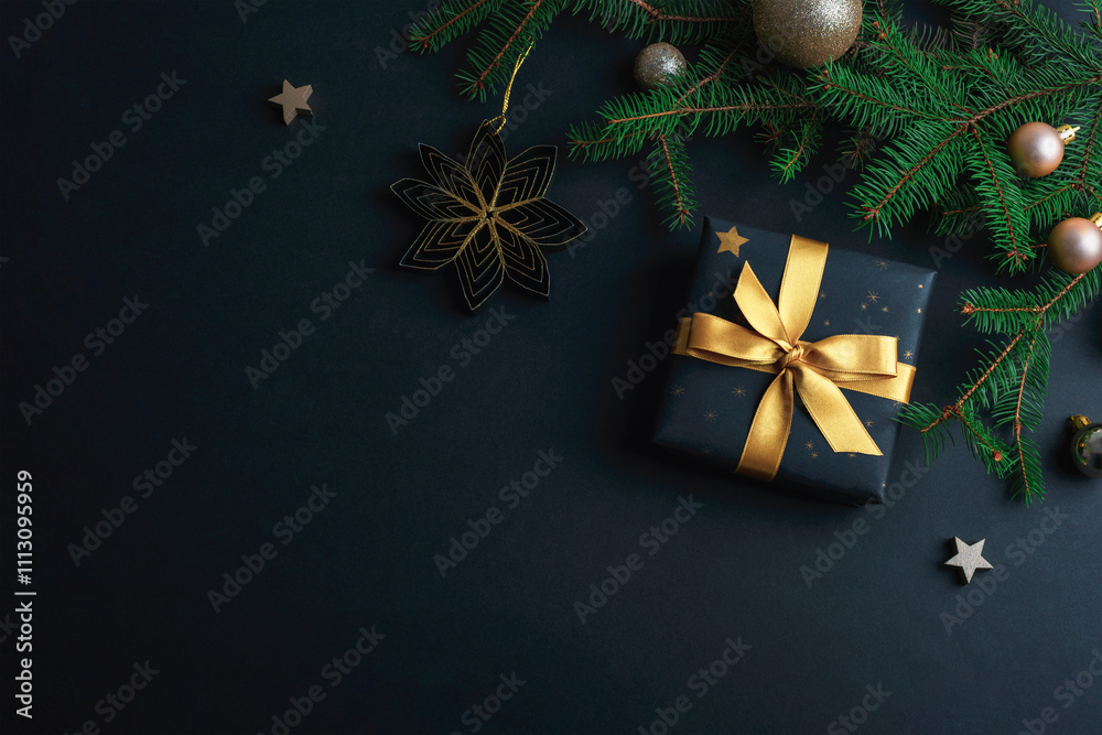 Christmas background with golden ornaments, stars, and a wrapped gift tied with a gold ribbon on black table. Top view, flat lay, copy space Christmas background with golden ornaments, stars, and a wrapped gift tied with a gold ribbon on black table. Top view, flat lay, copy space