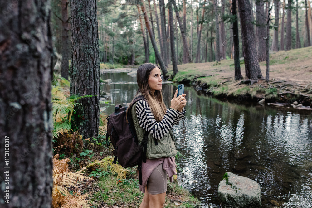 Hiker uses a smartphone to take a photo of a river in Sierra de Madrid Hiker uses a smartphone to take a photo of a river in Sierra de Madrid