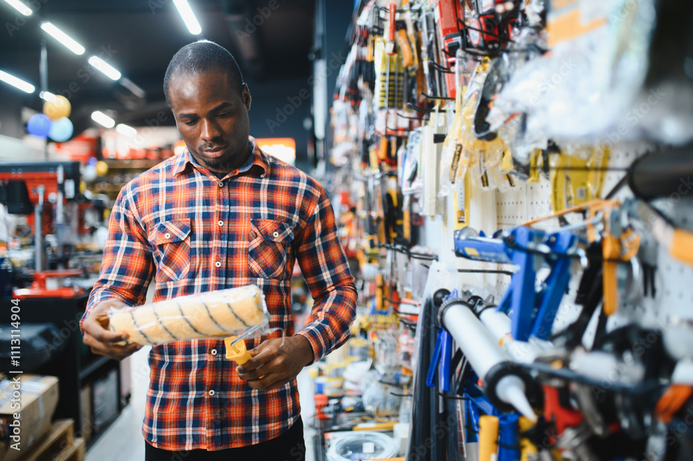 African american male customer in a modern hardware store chooses a paint roller African american male customer in a modern hardware store chooses a paint roller