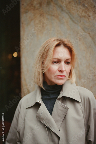 Woman in a Beige Coat Standing Near Textured Wall photo