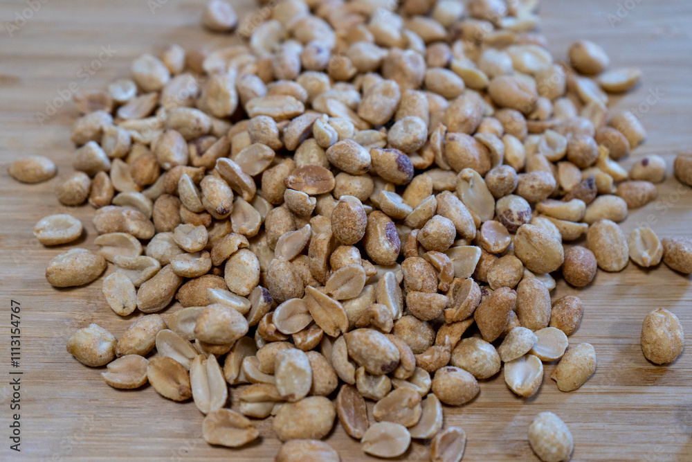 Fototapeta premium Peanuts spread out on a wooden board, highlighting their rustic and natural appeal.