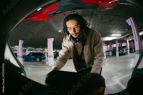 Man putting luggage on car trunk. Fisheye lens. photo