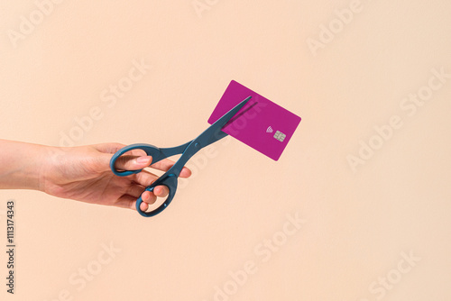 Person Cutting Credit Card With Scissors Against Beige Background photo