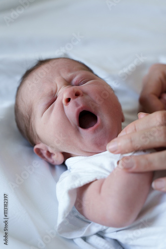 A newborn baby yawns in a hospital bed photo