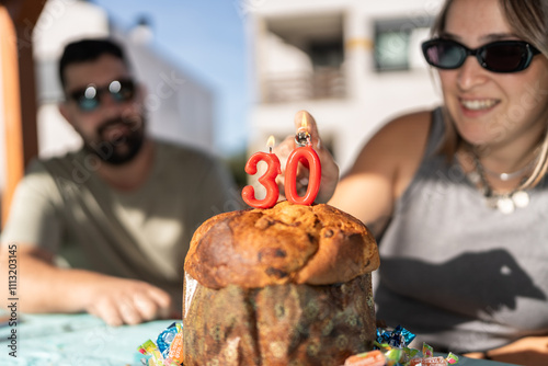 Woman lighting candles on a panettone for 30th birthday photo