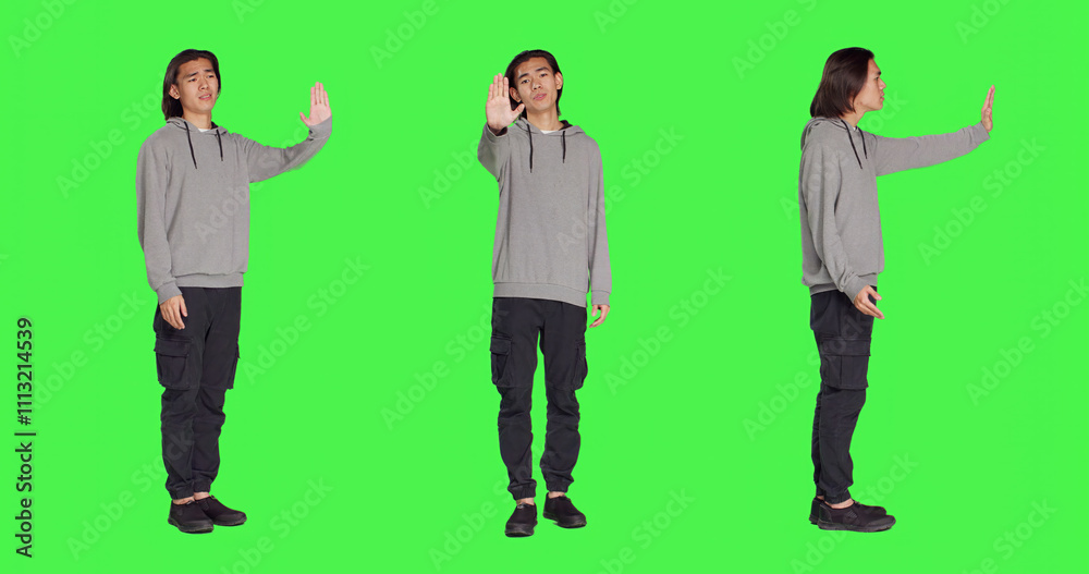 Obraz premium Person showing stop sign with palm raised in studio with greenscreen backdrop, advertising negativity and rejection on camera. Unhappy displeased man doing no gesture, disagreeing.