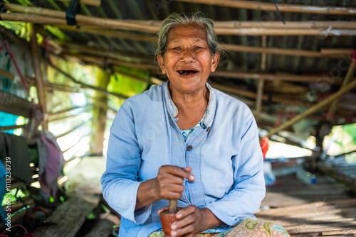 Smiling Elderly Thai Woman Chewing Betel Nut in Rural Thailand photo