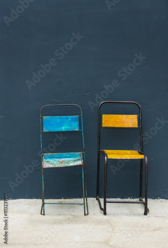 Vintage Blue and Yellow Metal Chairs Against Dark Wall photo