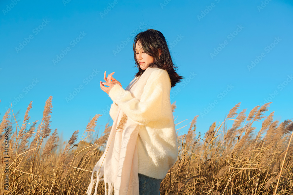 Obraz premium Beautiful woman dancing in the reeds on a sunny autumn afternoon