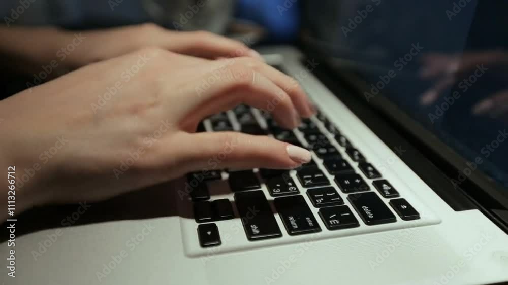Close-up of hands typing on a backlit laptop keyboard. Close-up of hands typing on a backlit laptop keyboard.