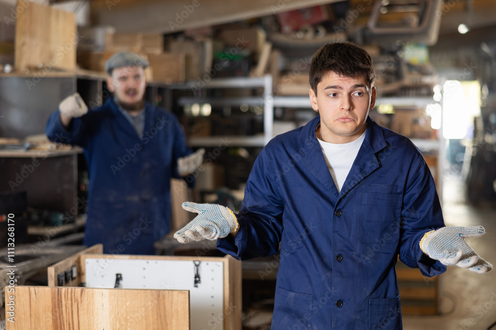 Young male carpenters quarrel during work process in wooden workshop Young male carpenters quarrel during work process in wooden workshop