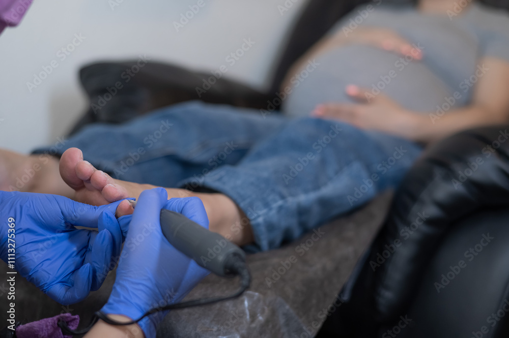 Pregnant woman on a hardware pedicure procedure in a beauty salon. Pregnant woman on a hardware pedicure procedure in a beauty salon.