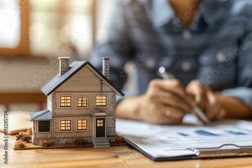 Real estate agent showcasing house model with man signing purchase contract, mortgage loan, property investment