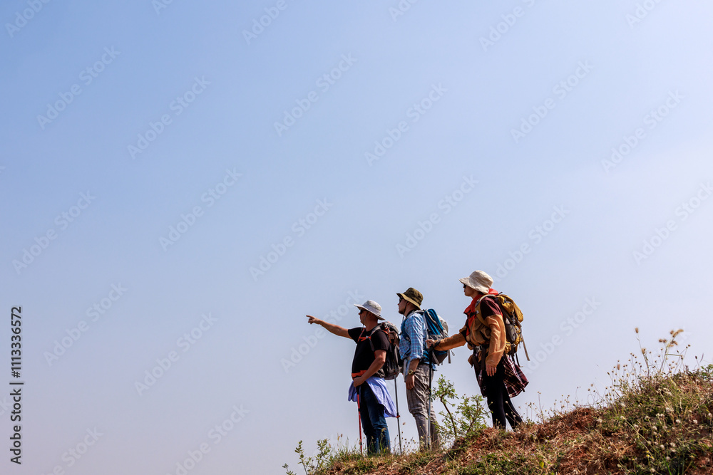  hikers are standing on mountain slope and looking away.