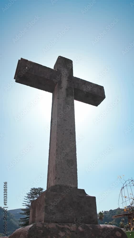 Sunlight glowing behind a majestic stone cross in a peaceful cemetery Sunlight glowing behind a majestic stone cross in a peaceful cemetery