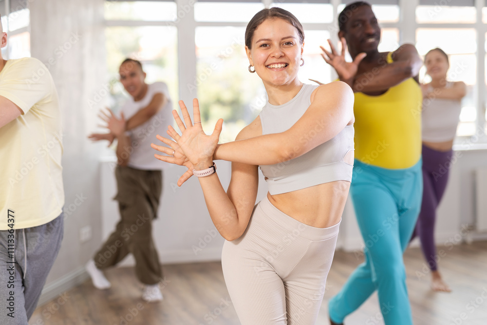 Fototapeta premium Dynamic young lady training active dance poses in dancehall during workout session