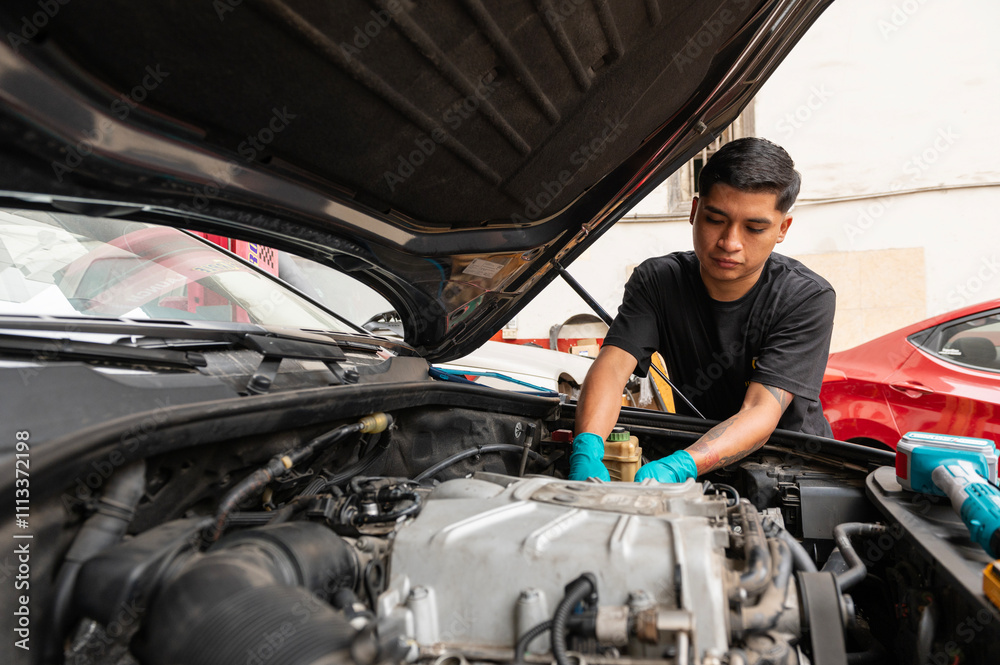Young latin mechanic fixing a car engine Young latin mechanic fixing a car engine