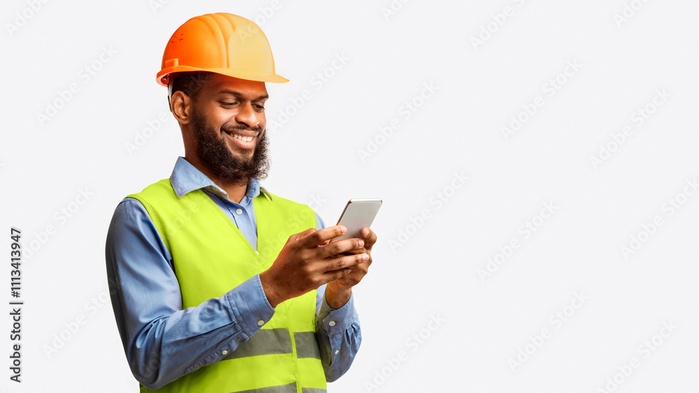 African Builder Worker Using Smartphone Building App Standing On White Studio Background. Panorama, Copy Space African Builder Worker Using Smartphone Building App Standing On White Studio Background. Panorama, Copy Space